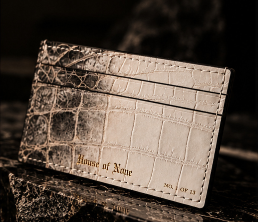 Angled view of the smoky grey-to-pearl crocodile leather cardholder with gold House of None detailing