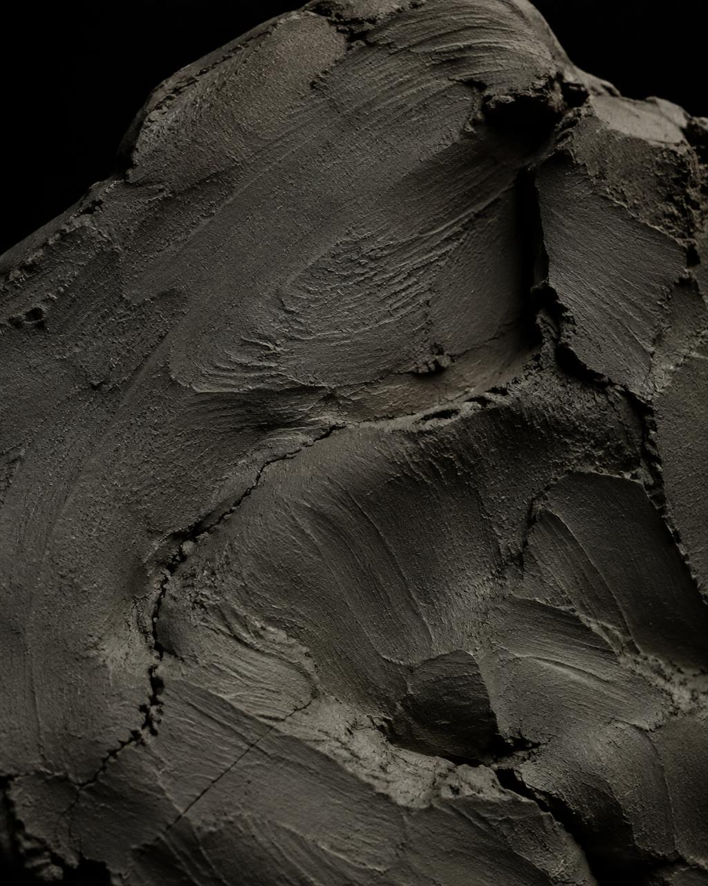 Raw dark clay surface marked by hand