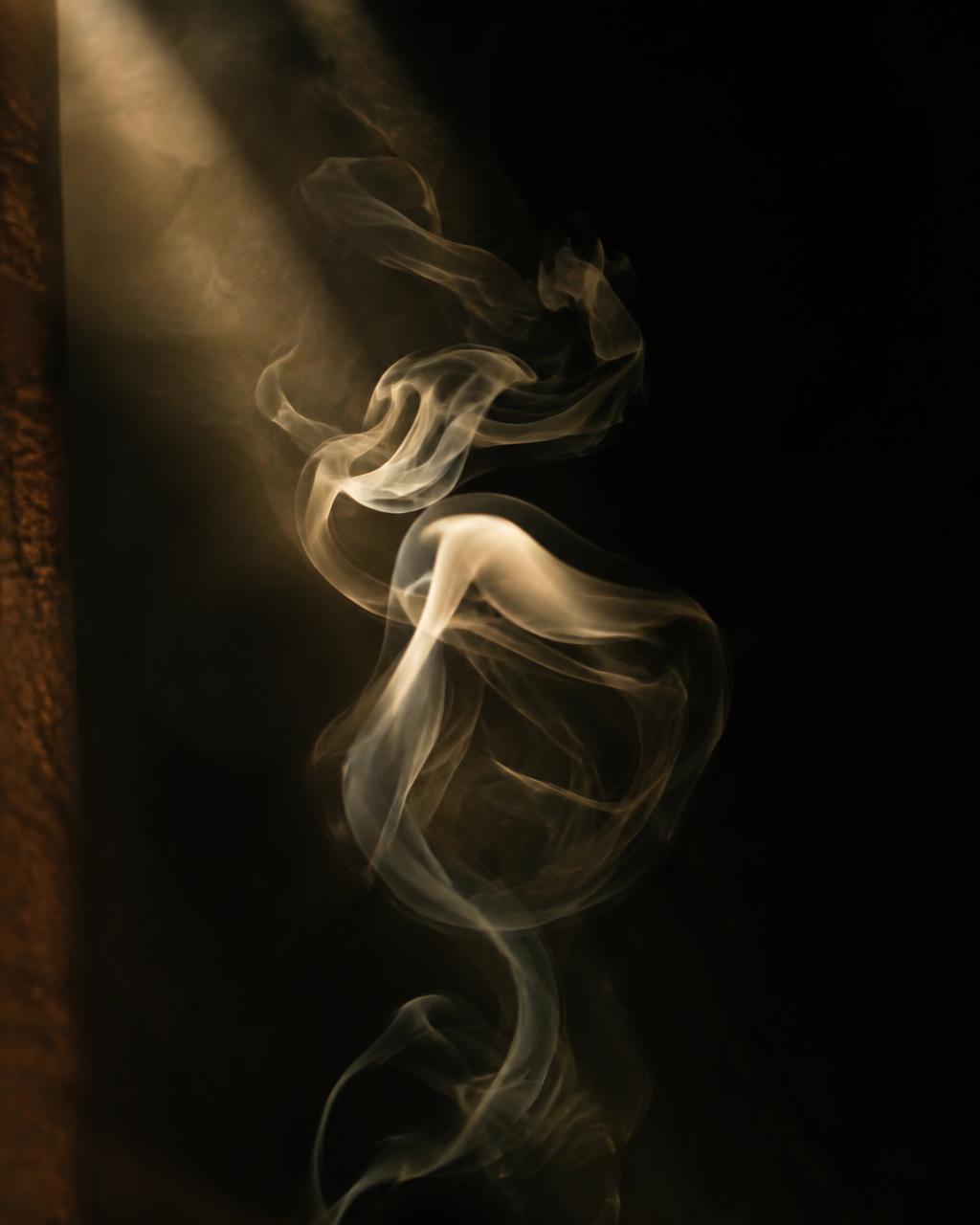 Smoke curling through a beam of warm light