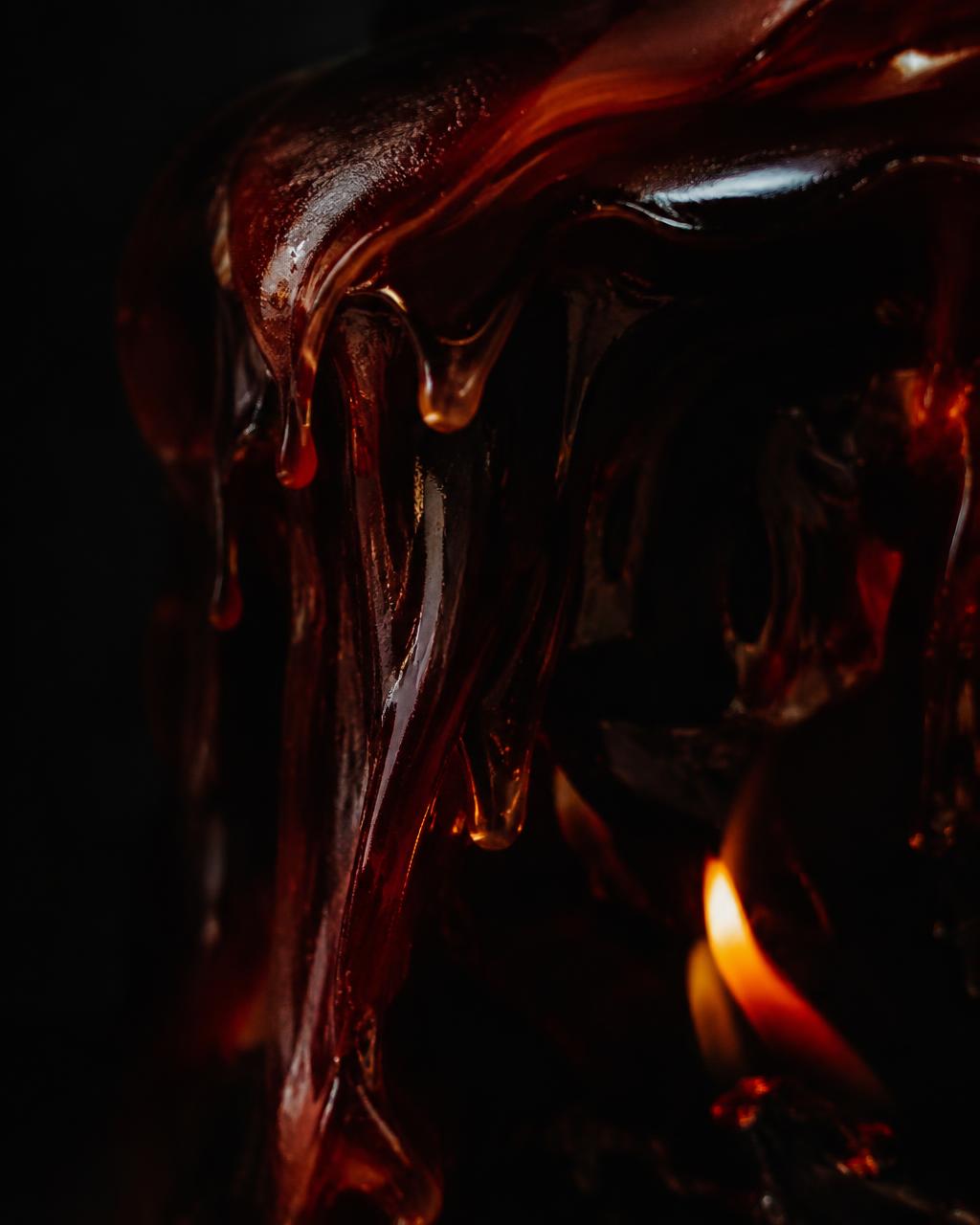 Dark molten wax beside a low flame